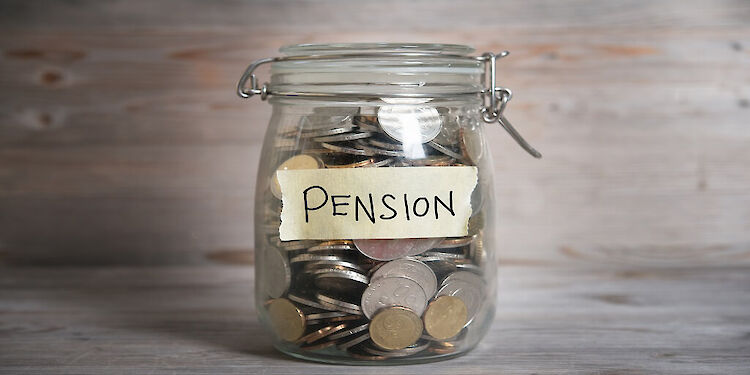 Een glazen potje gevuld met muntgeld met een briefje met 'pension' erop.