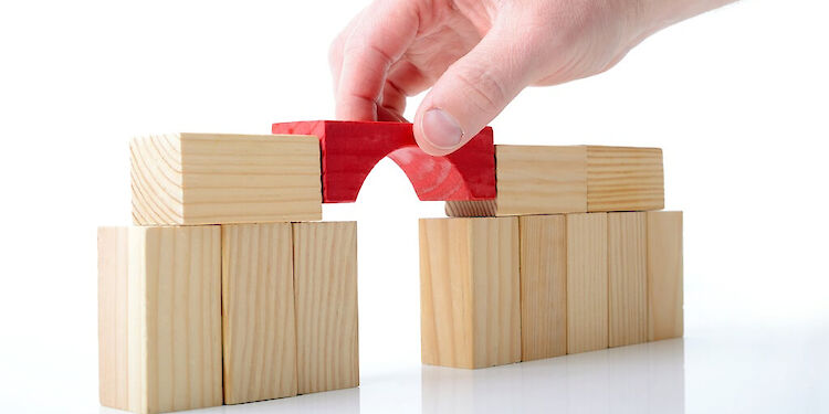 Stapel blokjes met een hand die een rood blokje tussen de andere blokjes legt om ze te verbinden