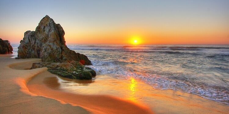 Zonsondergang op strand met rots
